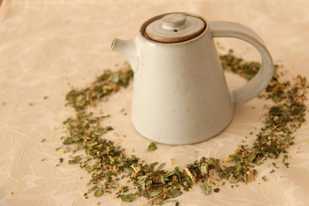 Minimalist ceramic teapot surrounded by a heart of dried herbs, perfect for tea enthusiasts.