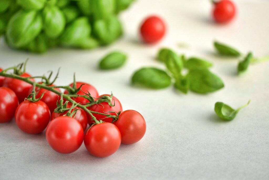 Vibrant fresh cherry tomatoes and basil on a marble background.