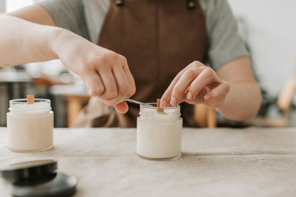 Close-up of artisan crafting handmade candles with wooden wicks in workshop.