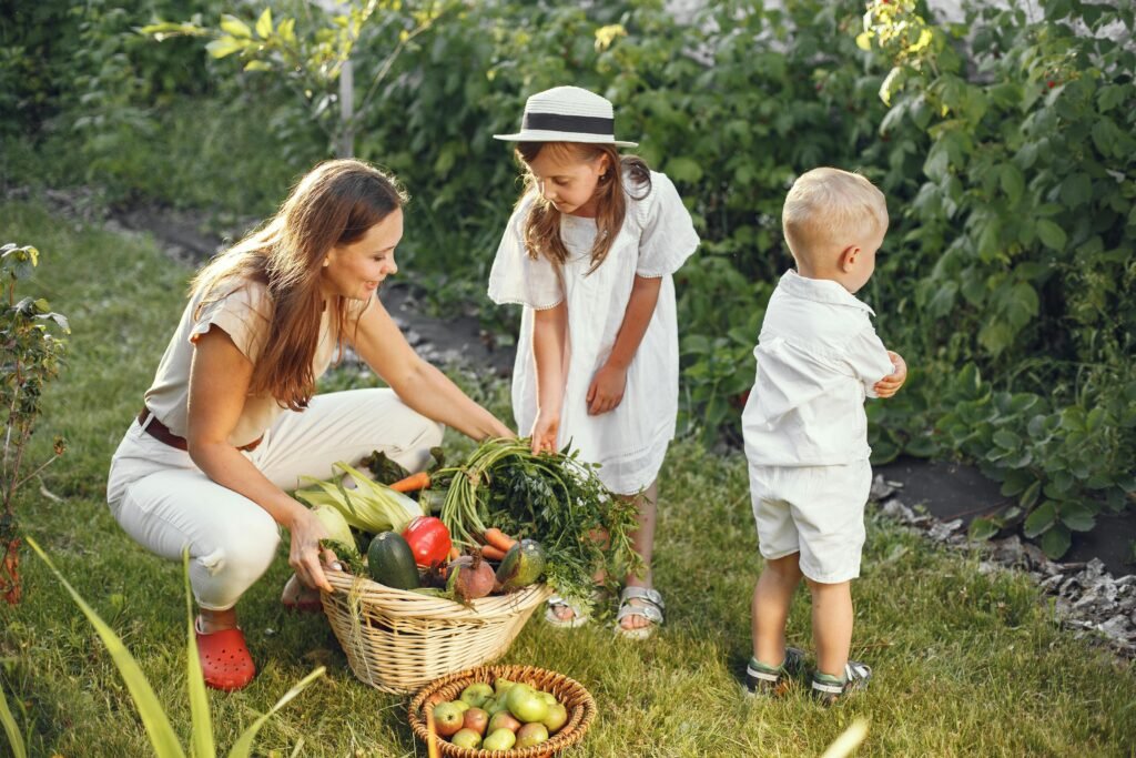 A mother and her children picking fresh vegetables in a sunny garden.